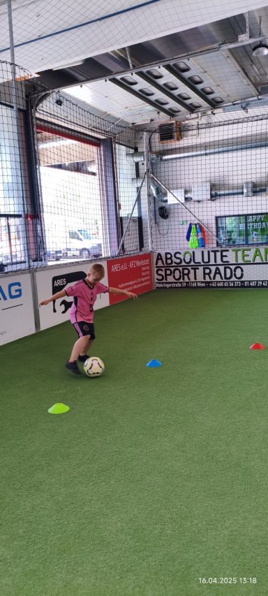 Ein Junge dribbelt einen Fußball auf einem Trainingsfeld mit bunten Conen.